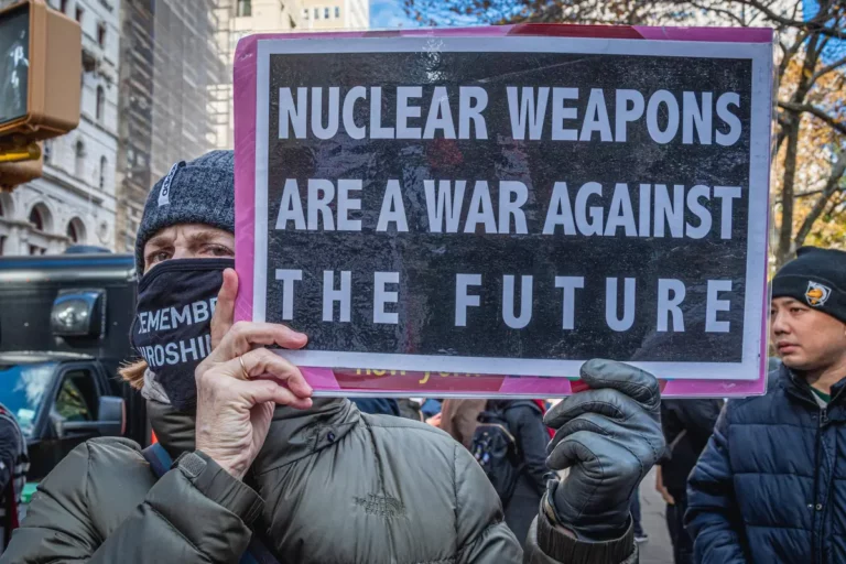 Un homme qui tient une pancarte "les armes nucléaires sont une guerre contre le futur".